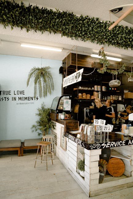 pexels-photo-3285137-3285137 Chic coffee shop interior featuring modern design, greenery, and counter service.